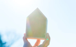 Une petite maison tenue au bout des doigts qui reçoit le soleil et la lumière